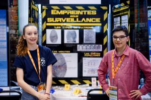 Un exposant et une exposante devant leur projet Empreintes sous surveillance!